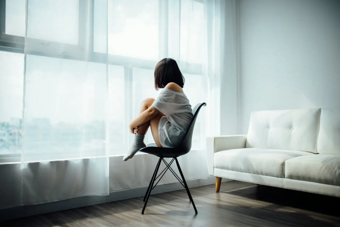 Mujer sentada junto a la ventana, pensativa
