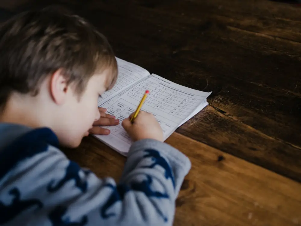 Niño concentrado escribiendo en su cuaderno